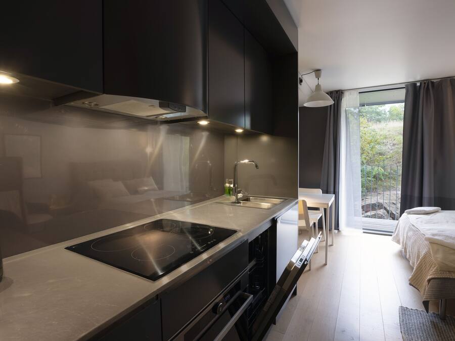A modern kitchen with a built-in stove, a sink, and a window overlooking a balcony.