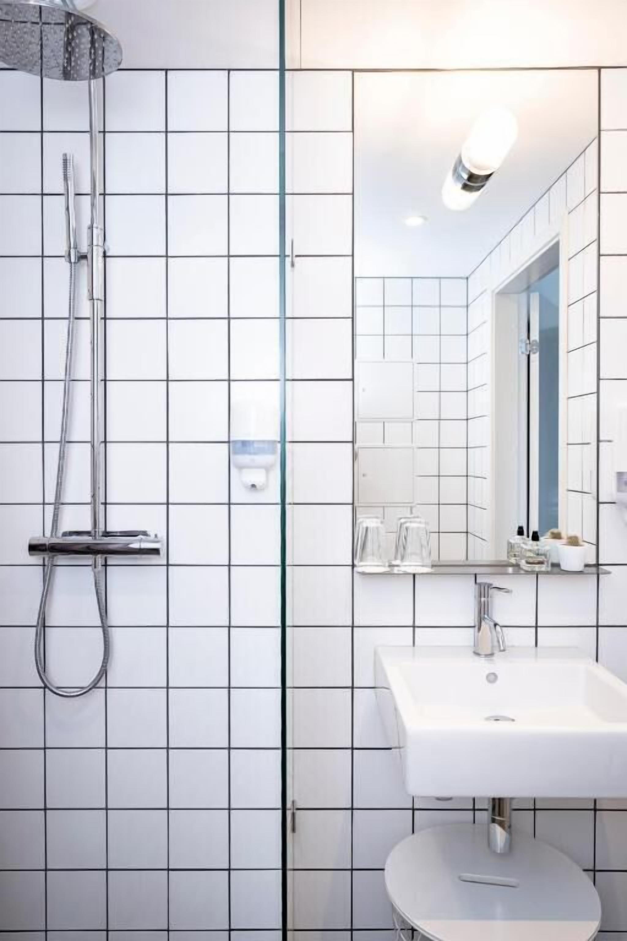 A modern bathroom with a shower, a sink, and a mirror.