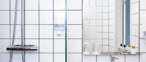 Un baño moderno con ducha, lavamanos y espejo.