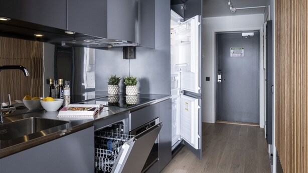 A modern kitchen with grey cabinetry, a dishwasher, and a refrigerator. - Hoom Home & Hotel (Jarfalla)