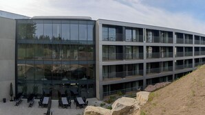 A modern building with a glass facade, outdoor seating area, and a landscaped courtyard. - Hoom Home & Hotel (Jarfalla)
