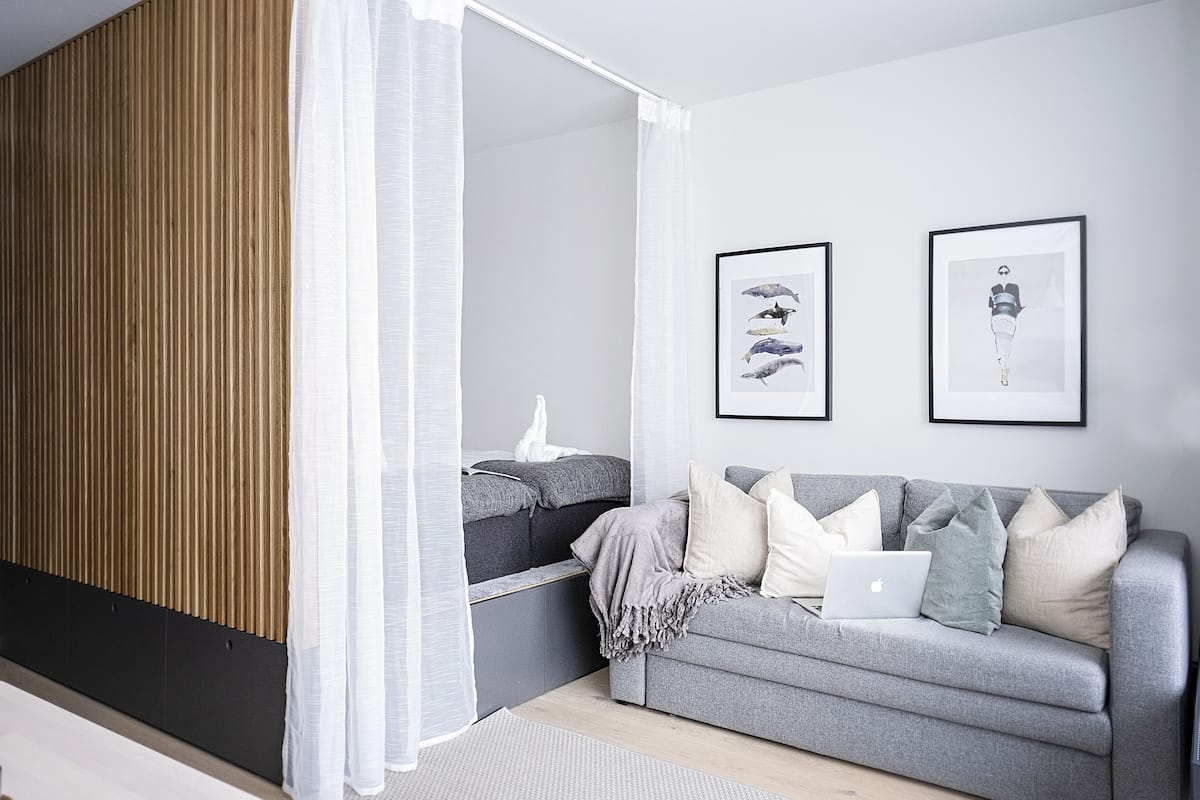 A modern living room with a grey sofa, a laptop, and two framed pictures on the wall.