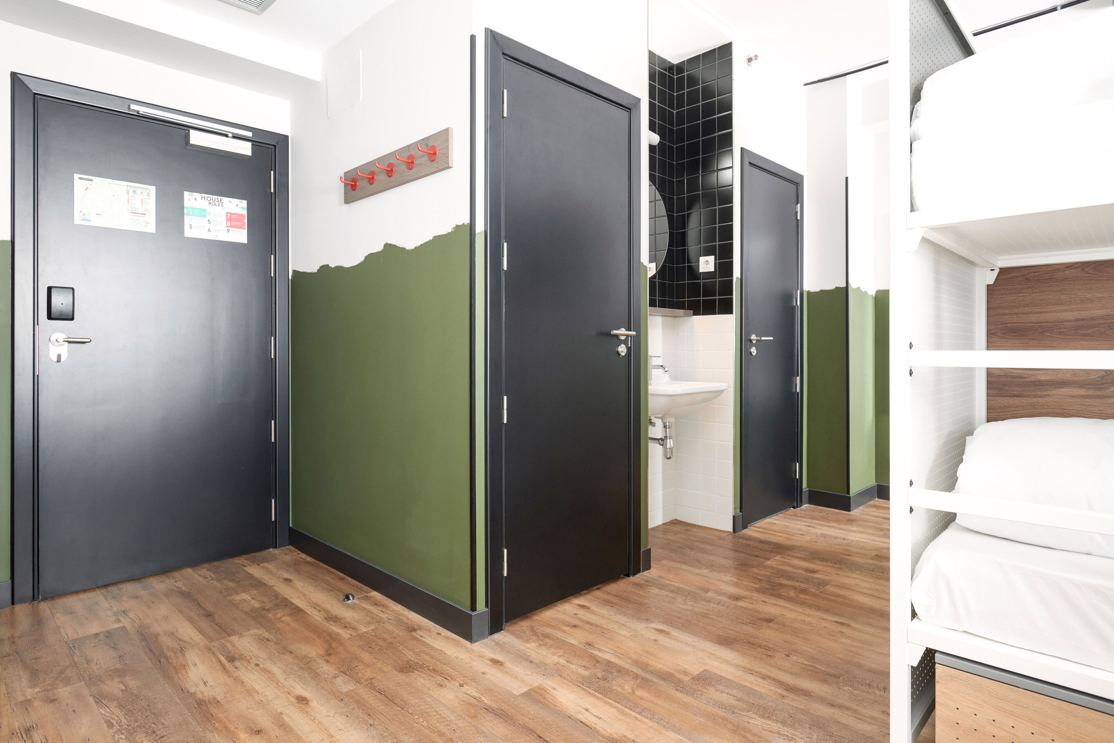 Une chambre d’hôtel avec un lit superposé, une salle de bain avec un lavabo et une porte avec une pancarte.