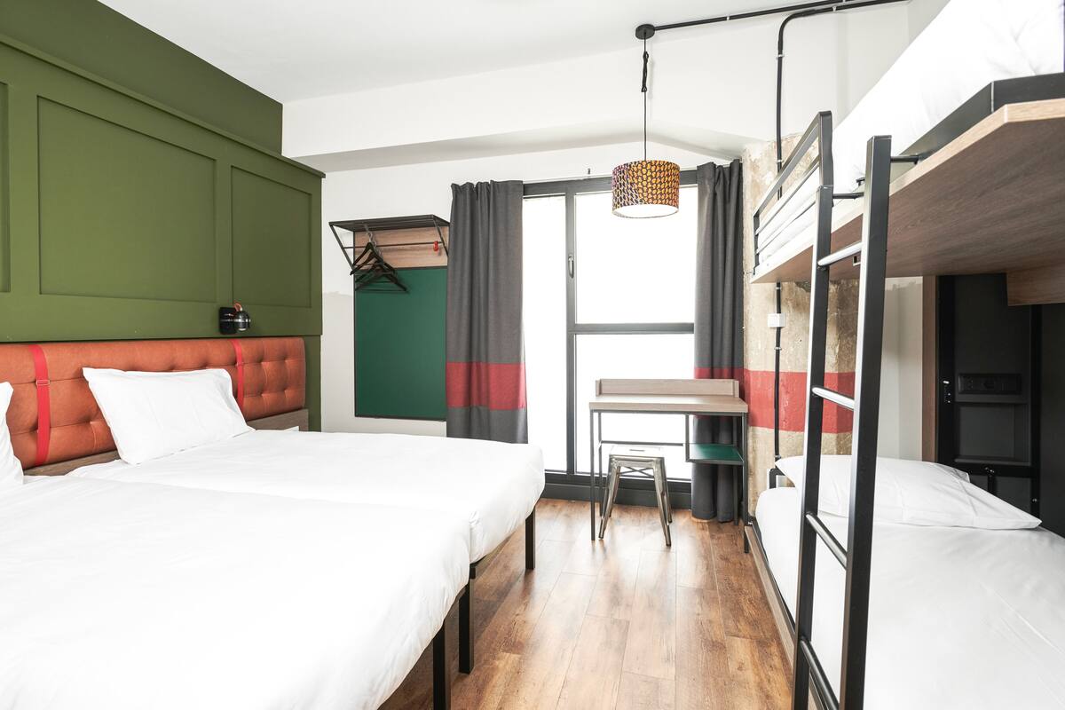 Una habitación de hotel con una cama litera, un escritorio y una silla.