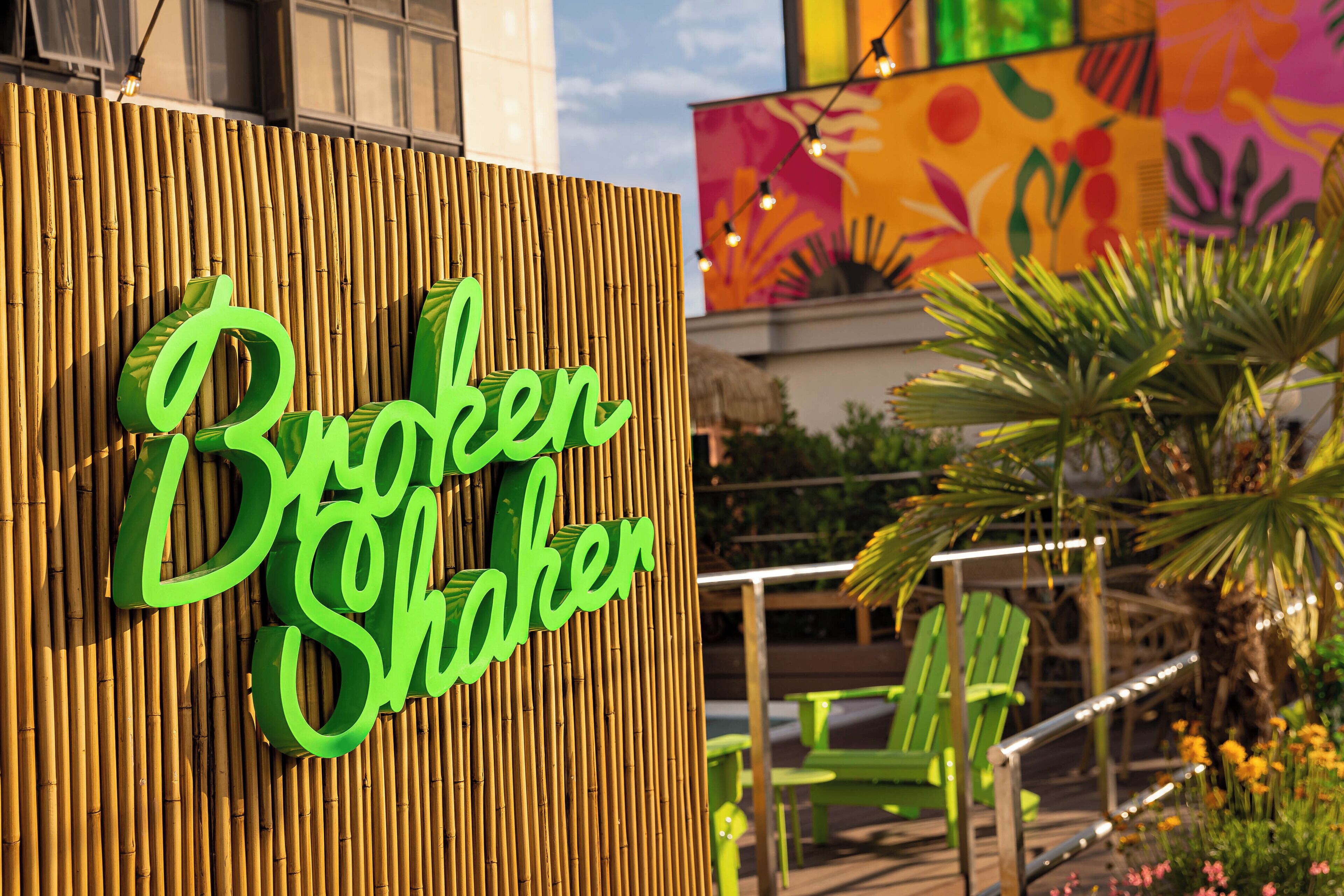 Parede de bambu com uma placa de neon que diz 'Broken Shaker'.