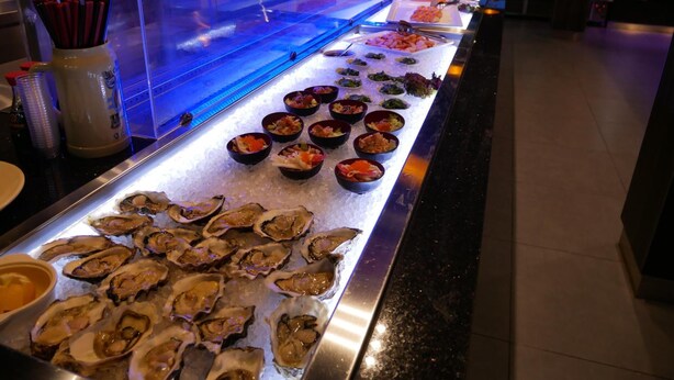 Un buffet proposant des plats de fruits de mer, notamment des huîtres et divers plats préparés.