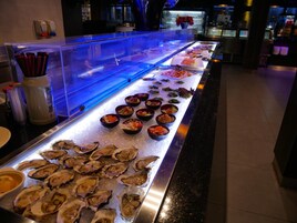 Buffet com opções de frutos do mar, incluindo ostras e diversos pratos preparados.