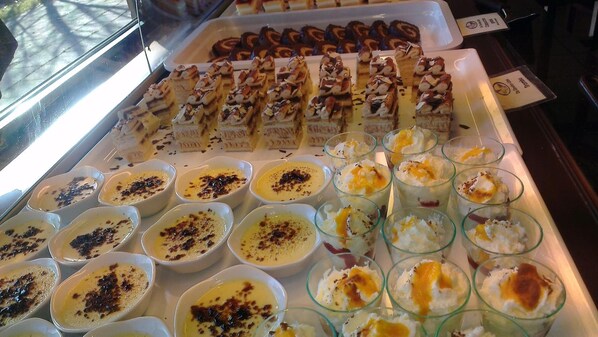 A dessert display with various pastries and custard-based desserts in bowls and glasses. - Hotel Het Oosten (Hazerswoude-Dorp)