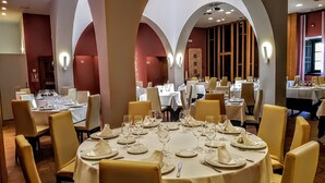 A restaurant with round tables set for dining, featuring white tablecloths and gold chairs.