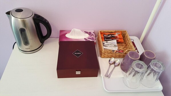 A table with a silver kettle, a tissue box, a basket of snacks, and a tray with cups and spoons. - Penzion U Lucerny (Jindrichuv Hradec)