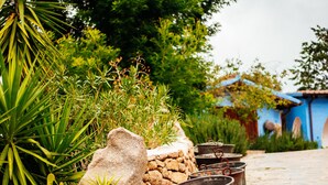 Un sendero de piedra flanqueado por macetas con plantas y una pared de piedra.