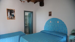 Una habitación con dos camas, una puerta y una mesita.