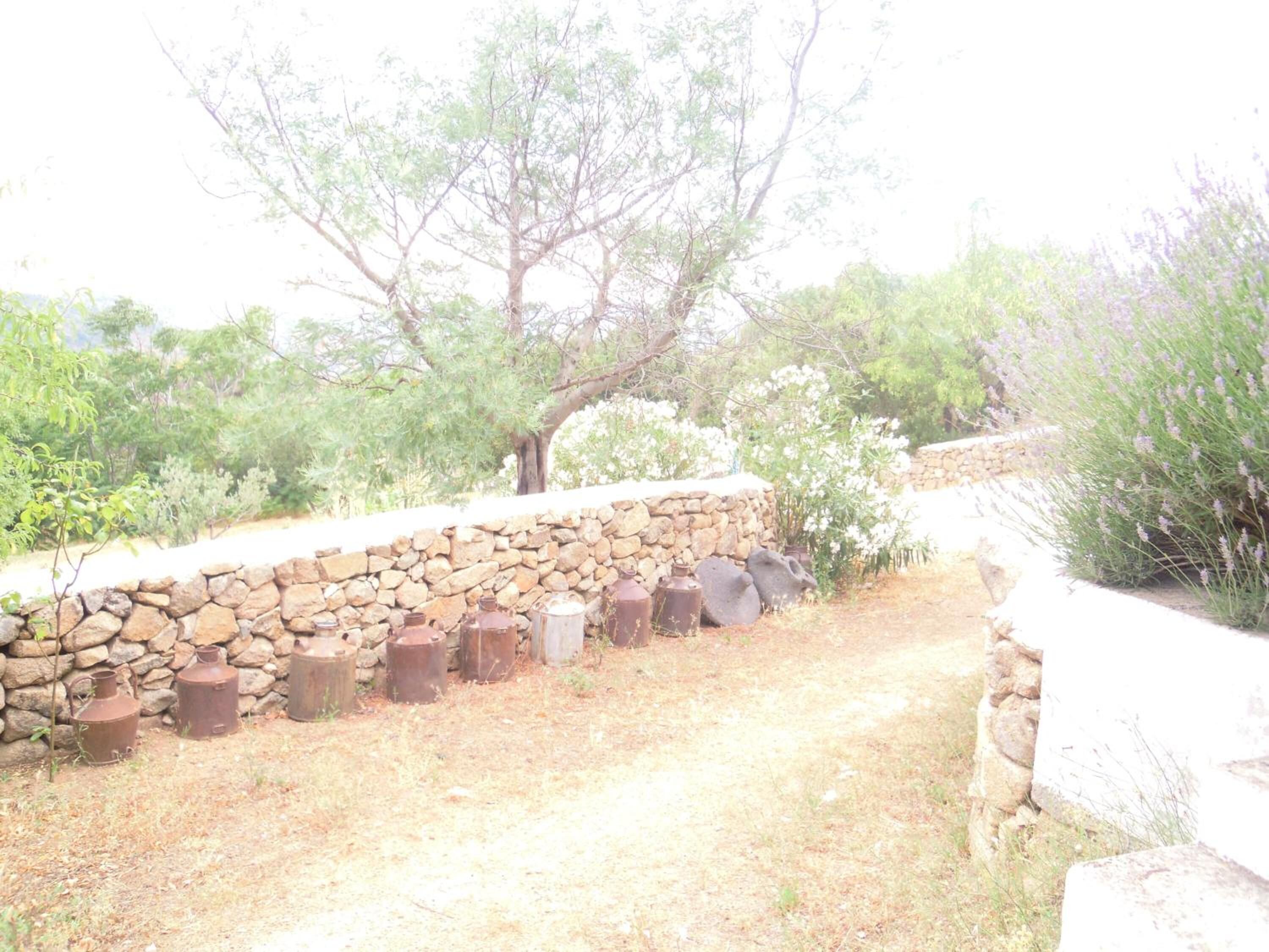 A stone wall with several rusted metal containers.