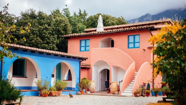 Un patio con un edificio que cuenta con arcos y una escalera que sube a la planta superior.