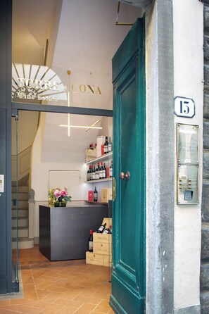 A hotel entrance with a teal door, a reception desk, and a staircase leading to an upper floor. - Borgodegreci Apartments (Florence)
