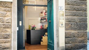 Entrada a una bodega, con fachada de piedra, puerta verde y una estantería de vino visible en el interior.