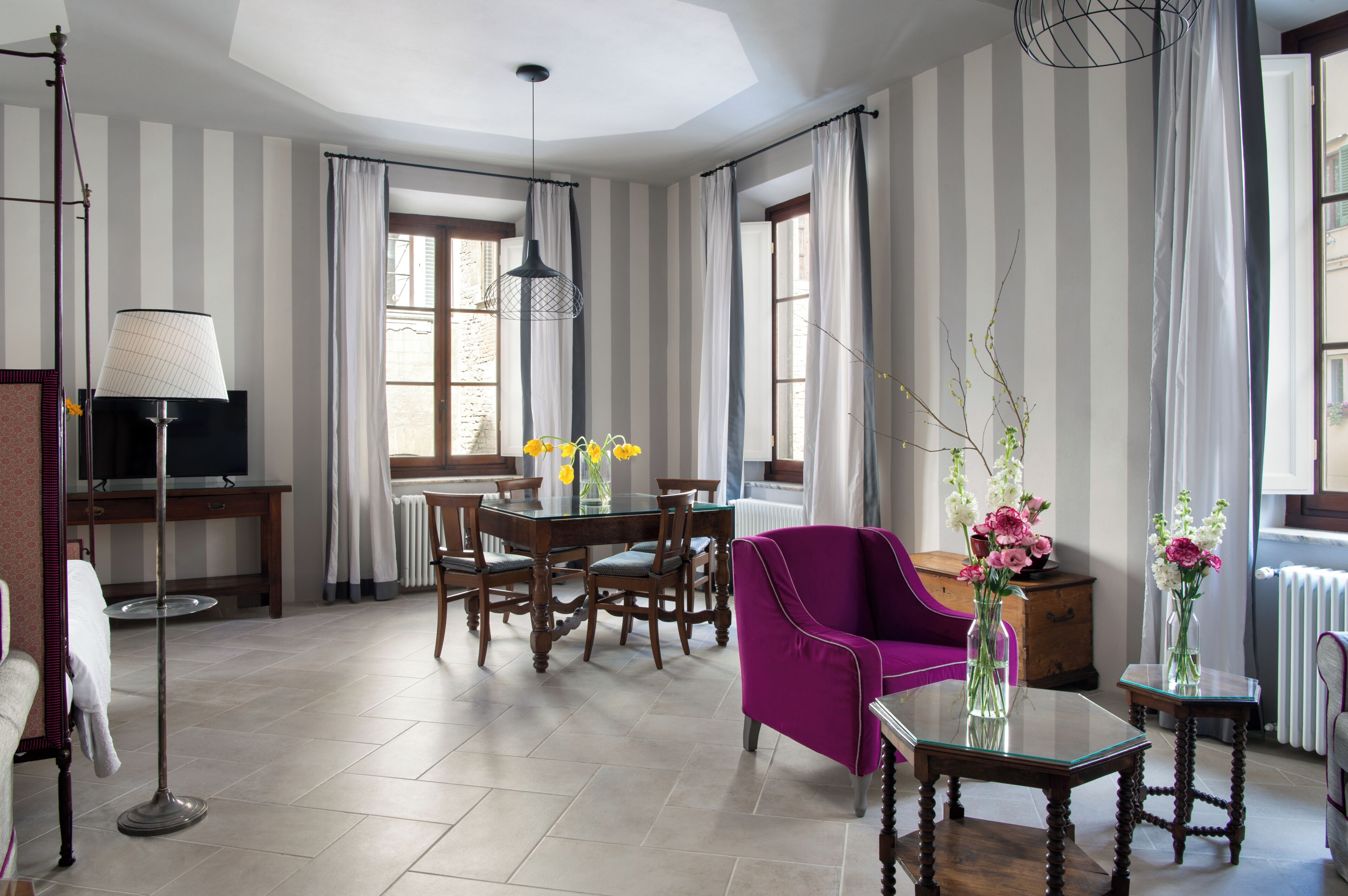 Une chambre d’hôtel avec un coin repas, un fauteuil violet, une table en verre et un téléviseur.