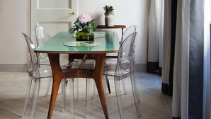 Un comedor con una araña, una mesa con sillas, un cuadro en la pared y una puerta.