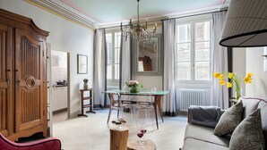 Amplia sala de estar con un aparador de madera, una mesa de comedor de vidrio y un sofá con cojines estampados.