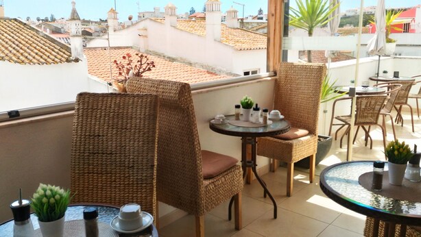 A balcony with wicker chairs, a small round table, and potted plants. - Suites Inn Lagos (Lagos)