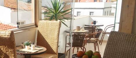 A balcony with wicker furniture, a potted plant, and a table with fruit.