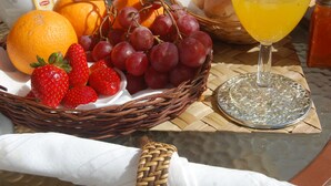 A wicker basket filled with strawberries, grapes, and oranges on a table. - Suites Inn Lagos (Lagos)