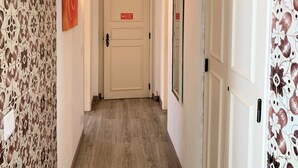 A hallway with patterned wallpaper, a door with a sign, and a light fixture. - Suites Inn Lagos (Lagos)