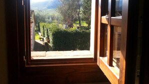 A window with a view of a garden and mountains. - Agriturismo Pretenzano (Volterra)