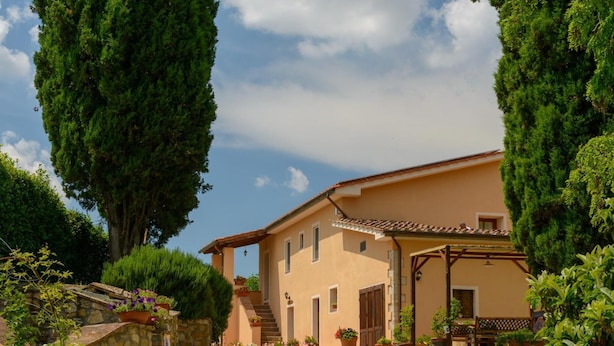 A two-story building with a stone facade, a tiled roof, and a covered porch. - Agriturismo Pretenzano (Volterra)