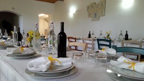 A dining area with round tables set for a meal, each with plates, glasses, and bottles. - Agriturismo Pretenzano (Volterra)