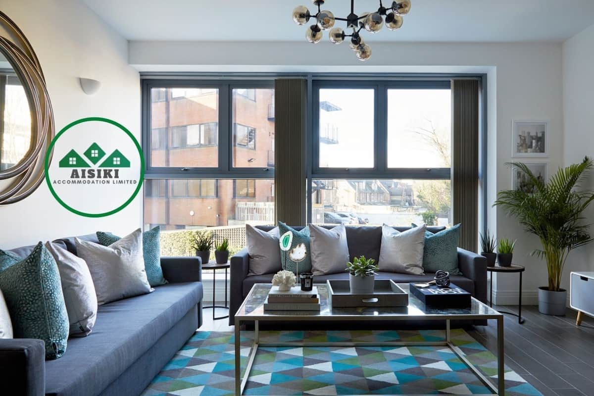 A modern living room with a sofa, coffee table, and large windows offering a view of the city.