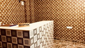 Un mostrador de recepción con un cartel que dice 'RECEPTION' en una habitación con paredes estampadas y suelo texturizado.
