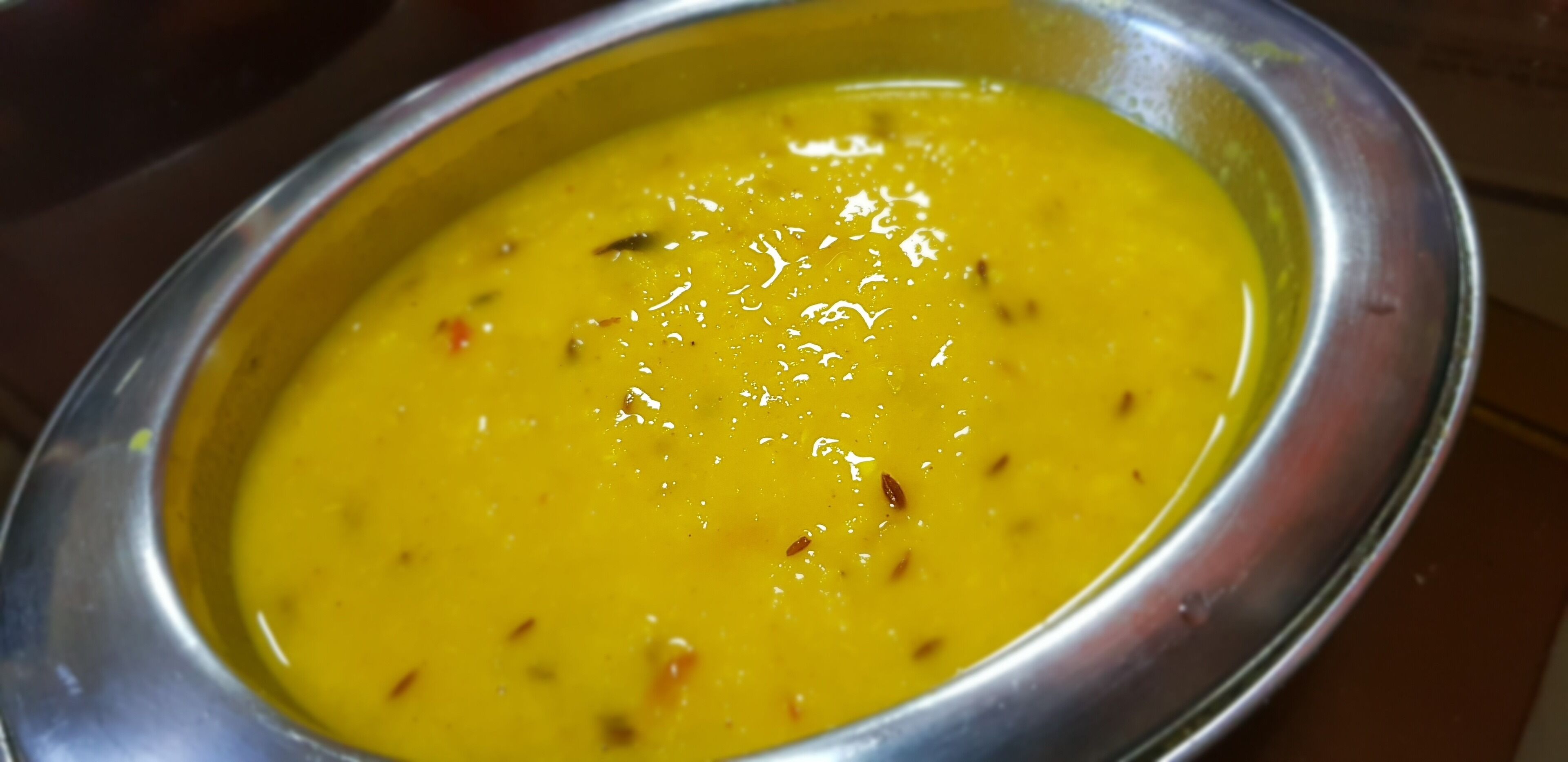 Una ciotola di zuppa gialla con spezie ben visibili.