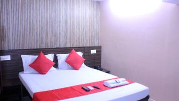 A hotel room with a bed, a nightstand, and a wall-mounted light.