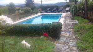 Una piscina al aire libre, sombrillas, sillones reclinables de piscina