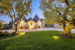 A stone building with a triangular roof, a paved driveway, and a well-maintained lawn. - Tenuta Odegitria (Martina Franca)