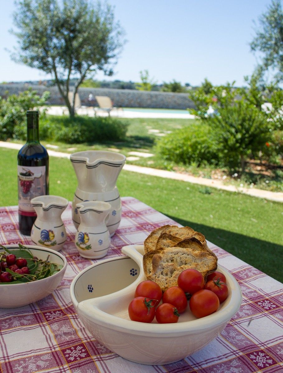 Une table dressée à l’extérieur, avec une bouteille, des bols et du pain.