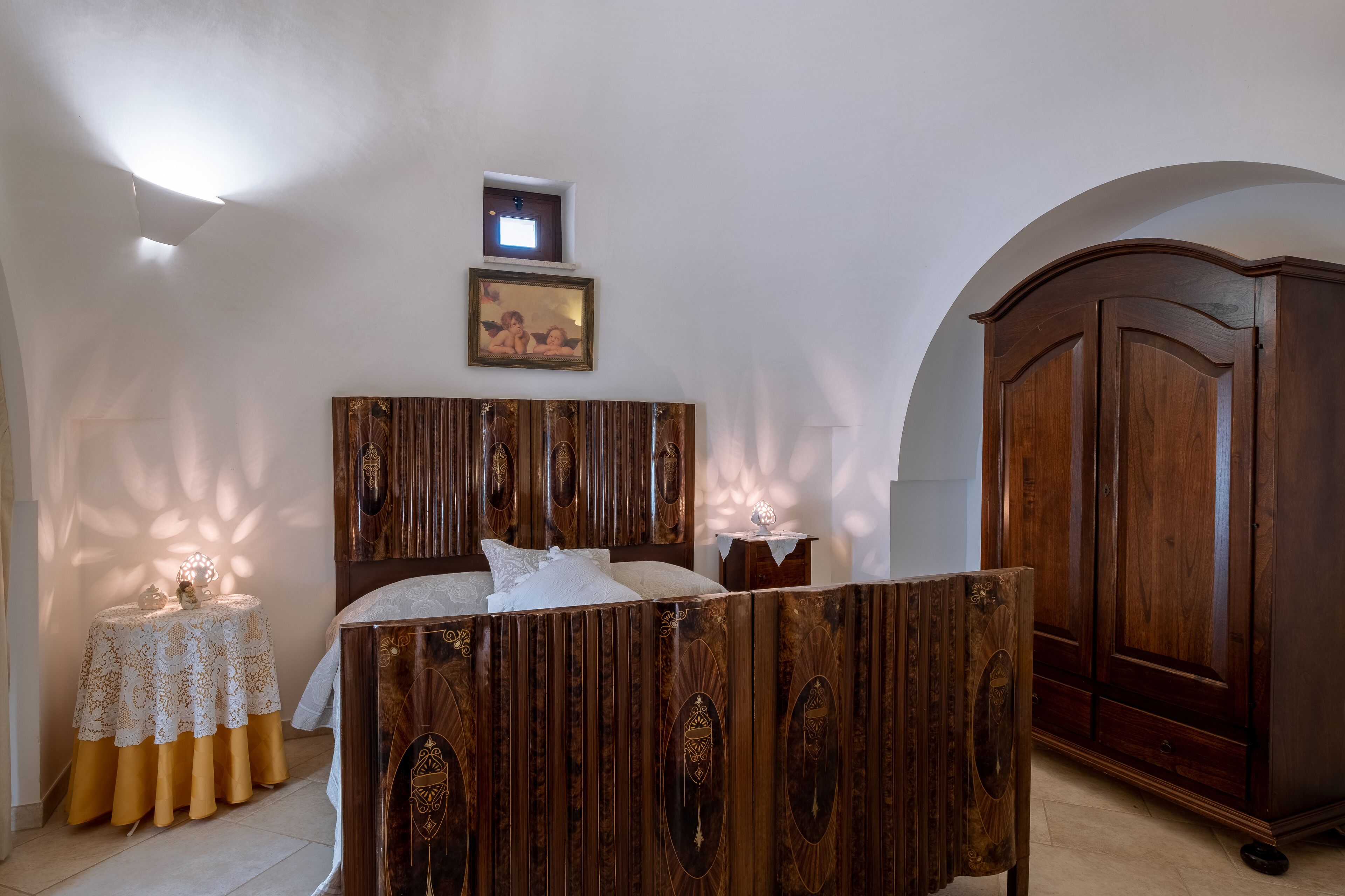 A bedroom with a wooden bed, a nightstand, a wardrobe, and a framed picture on the wall.