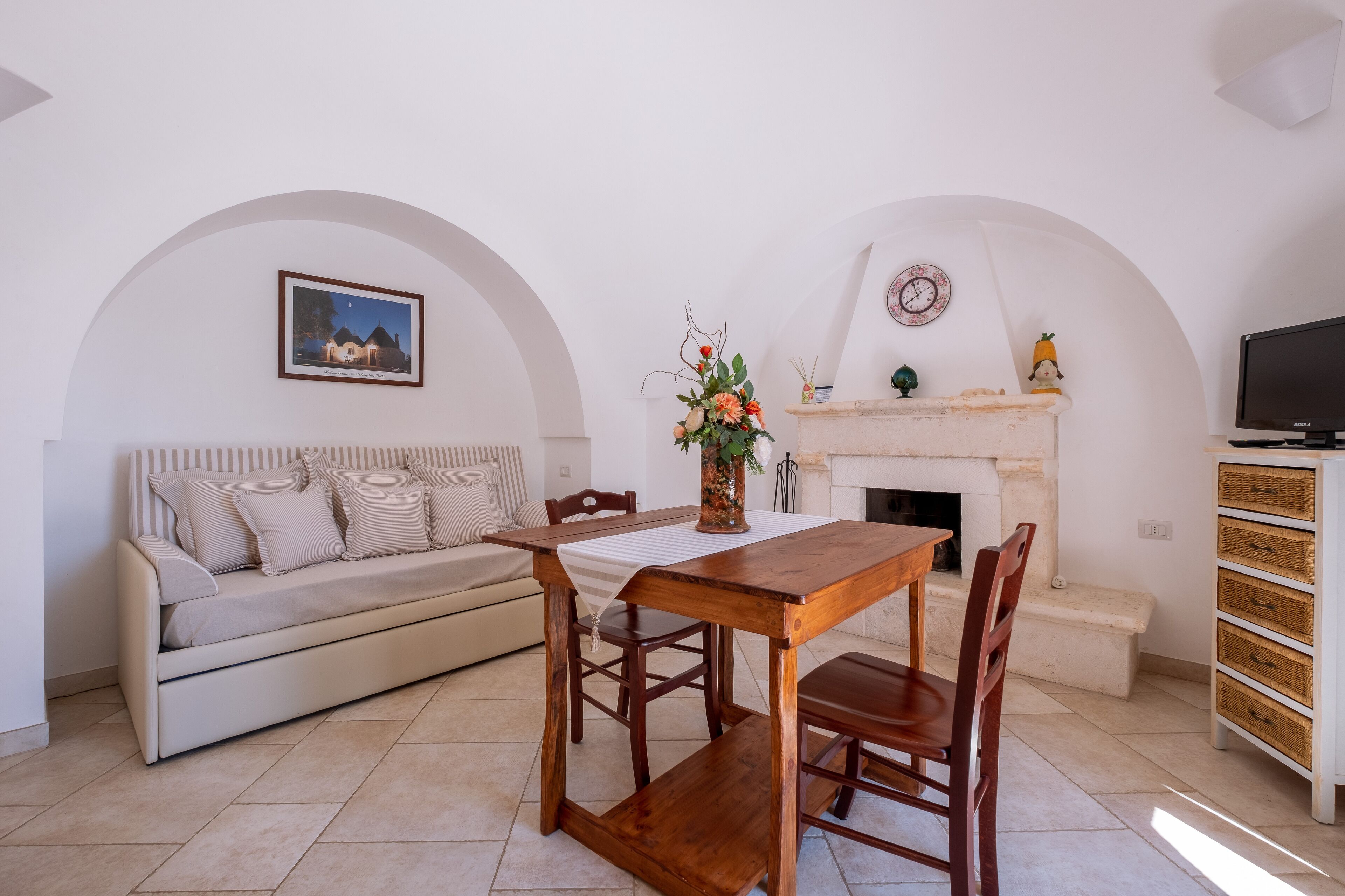 Una sala de estar acogedora con sofá, mesa de comedor de madera, sillas, chimenea y televisor.