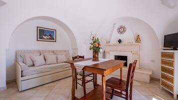 Una sala de estar acogedora con sofá, mesa de comedor de madera, sillas, chimenea y televisor.