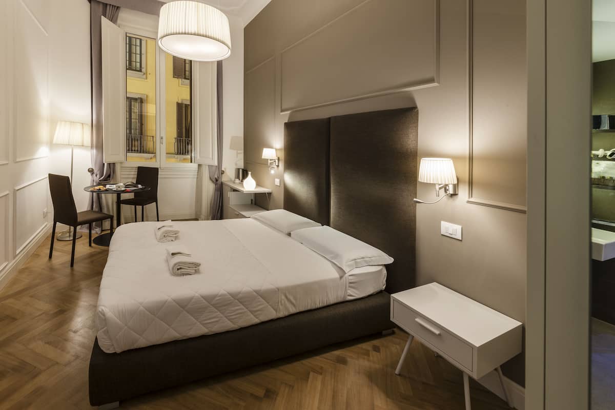 Una habitación de hotel moderna con una cama grande, mesitas de noche, un escritorio y una silla.