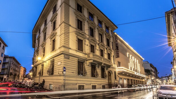 Un edificio histórico con un llamativo letrero de 'Hotel', arquitectura clásica y vista a la calle con vehículos.