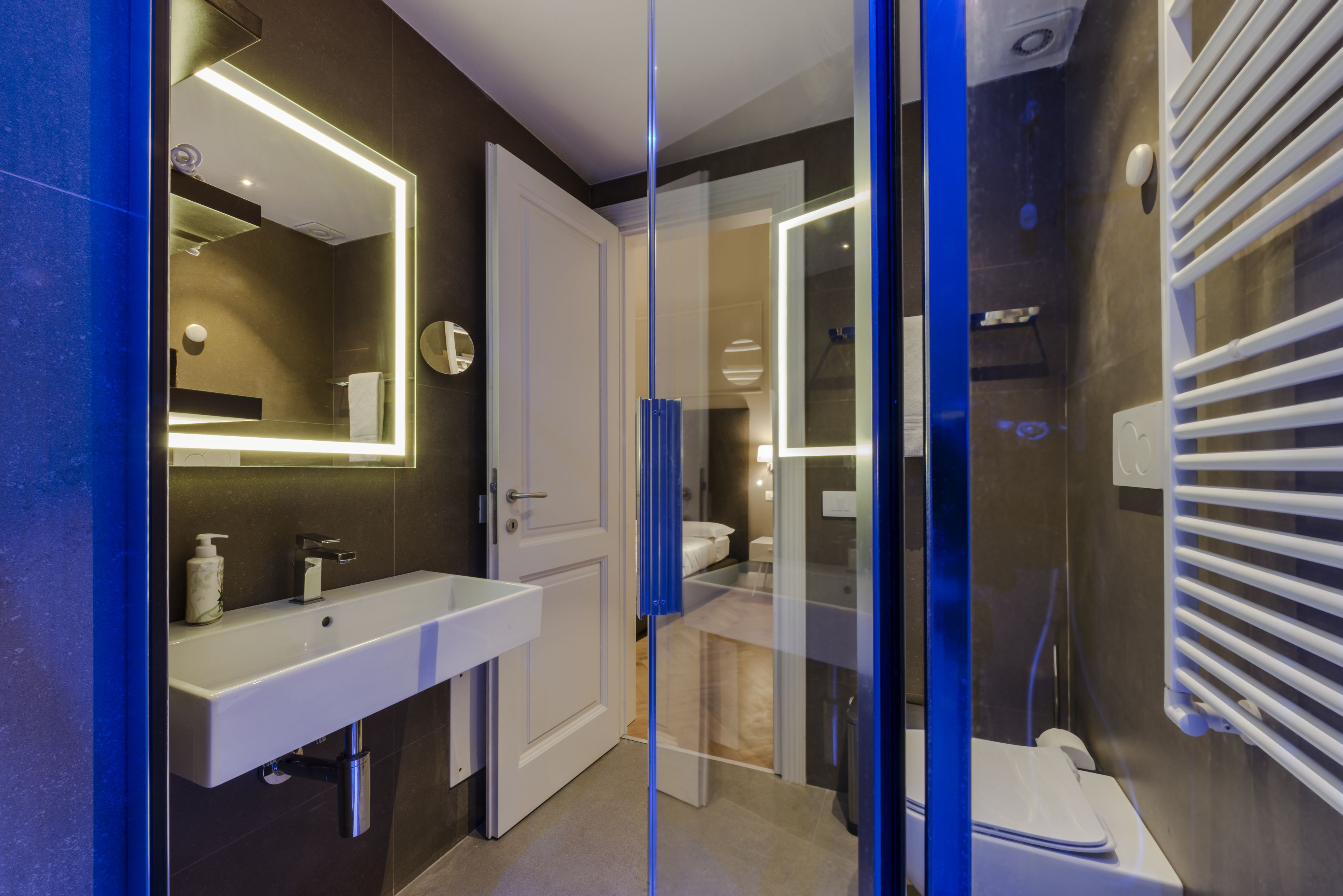 A modern bathroom with a glass-enclosed shower, a white sink with a mirror, and a white toilet.