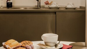 Una encimera de cocina con una taza de café, un hervidor y bolsitas de té.