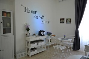 A cozy room with a white cabinet, a small table with a coffee machine, and a wall with a 'Home Sweet Home' sign.