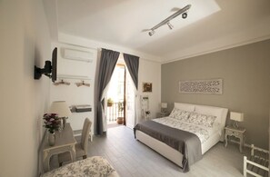 A bedroom with a bed, bedside tables, a desk, and a chair. There is a window with curtains, a ceiling fan, and a wall-mounted TV. - MyRooms San Pietro (Rome)