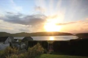 A sunset over a body of water with a small building in the foreground.