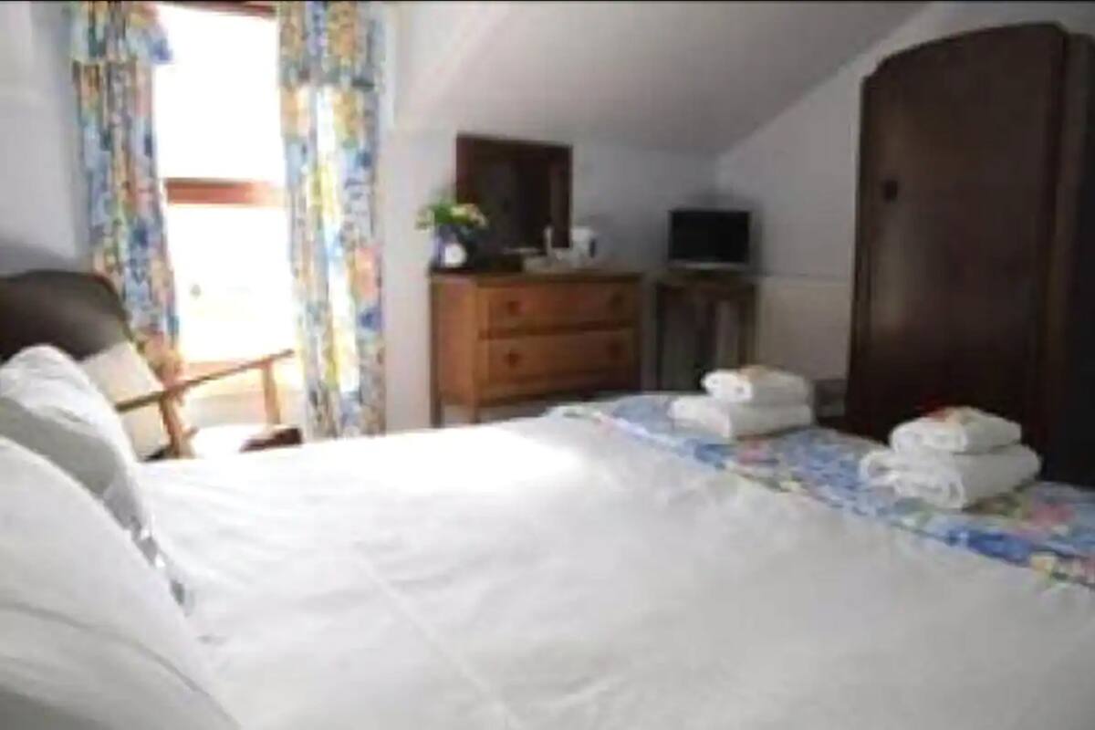 A hotel room with a bed, a dresser, a television, and a wardrobe.