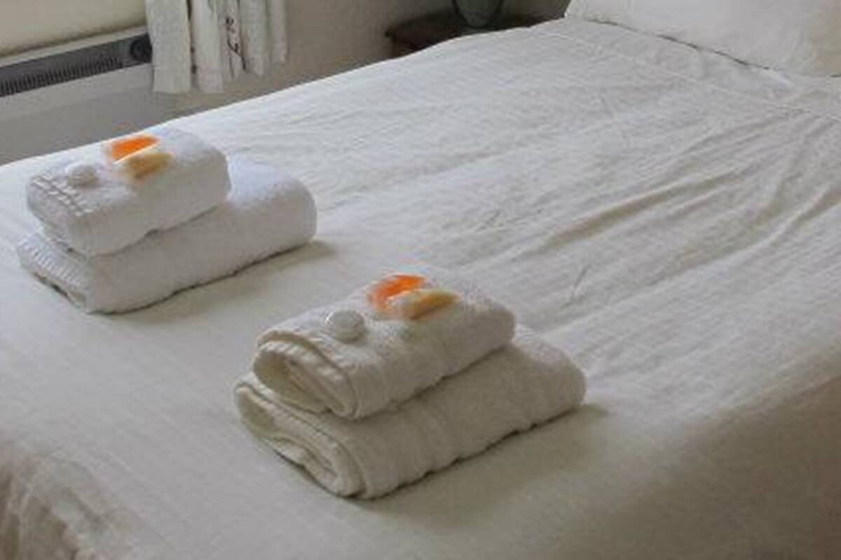 A neatly made bed with two folded towels placed on it.