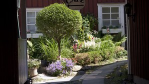 A garden with a cafe sign, a pathway, and various plants. - Garvaregården Hotel and B&B (Askersund)